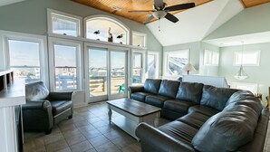 A spacious living room with a large sectional sofa, a coffee table, and a ceiling fan. - 5728- Wench's Pad - Semi-Oceanfront Nags Head | Pool & Hot Tub (Nags Head)