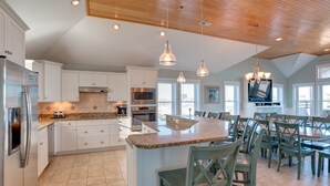 A spacious kitchen with white cabinetry, granite countertops, and a central island with seating. - 5728- Wench's Pad - Semi-Oceanfront Nags Head | Pool & Hot Tub (Nags Head)