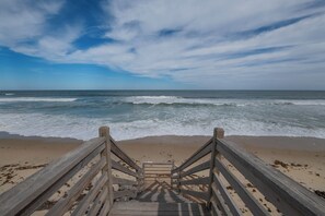 A wooden staircase leading to a beach with waves in the background.