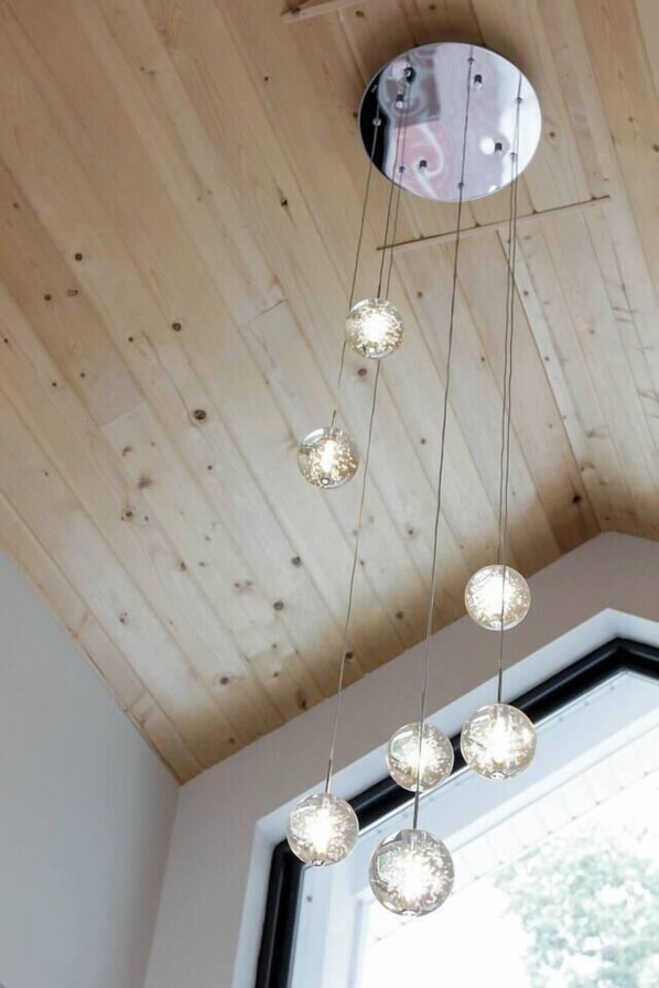 Eine Decke mit Holzbalken und einer runden Leuchte mit mehreren Glühbirnen.