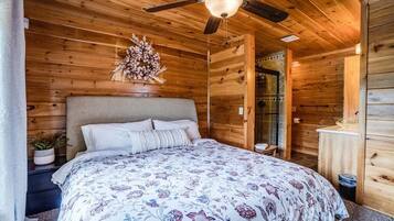 Une chambre dans une cabane en bois, avec un lit, un ventilateur de plafond et un élément décoratif mural.