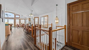 A spacious room with a wooden staircase, large windows, and a view of the ocean. - 5785- Southern Comfort - South Nags Head Oceanfront Retreat (Nags Head)