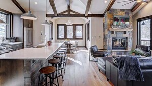A modern kitchen with a large island, bar stools, and a fireplace.