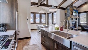 A modern kitchen with a large island, stainless steel appliances, and a stone fireplace.