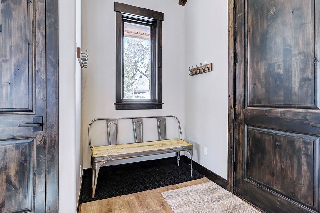 A hallway with a bench, a window, and a coat rack.