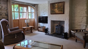 A cozy living room with a stone fireplace, a television, and comfortable seating. - A characterful former Carriage House, located in peaceful scenic countryside (Cellan)