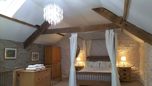 A bedroom with a stone wall, wooden furniture, a canopy bed, and a chandelier. - A characterful former Carriage House, located in peaceful scenic countryside (Cellan)