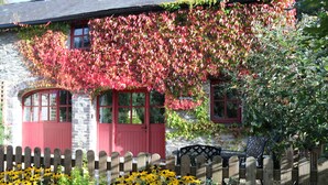 A stone building with red shutters and a wooden fence. - A characterful former Carriage House, located in peaceful scenic countryside (Cellan)