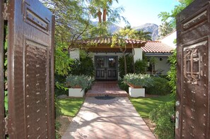 A pathway leading to a house with a tiled roof and a door with a decorative metal design. - Old Las Palmas Pickford Estate/Walk To Everything/Pool-Spa, Firepit,Rooftop Deck (Palm Springs)