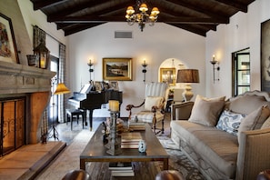 A cozy living room with a fireplace, a piano, a sofa, and a coffee table. - Old Las Palmas Pickford Estate/Walk To Everything/Pool-Spa, Firepit,Rooftop Deck (Palm Springs)