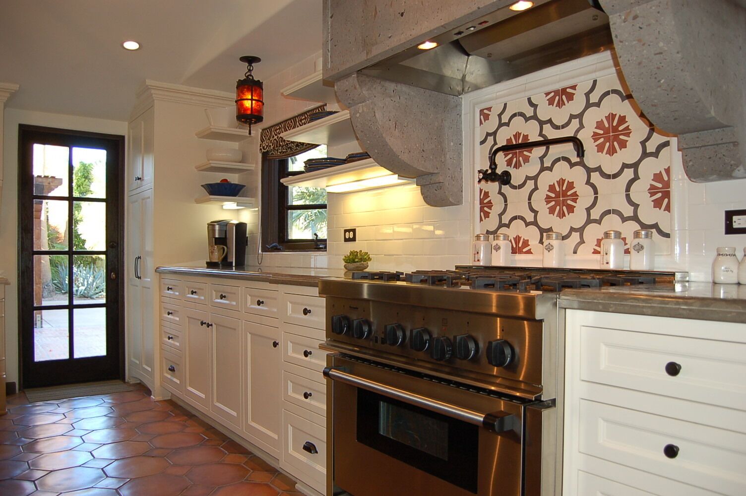 A kitchen with white cabinetry, a stainless steel stove, and a patterned backsplash.