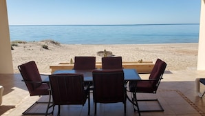 An outdoor dining area with a view of the beach and sea.