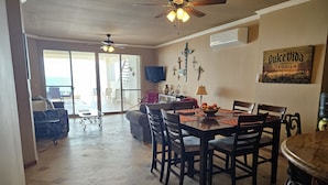 A dining area with a wooden table and chairs, a ceiling fan, and a view to the outside.
