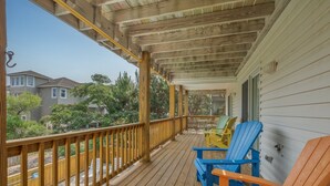 Um deck de madeira com móveis para área externa, uma área coberta e vista para casas vizinhas.
