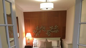 Et soveværelse med seng, natbord, lampe og en dekorativ genstand på væggen.