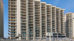 A multi-story residential building with balconies, a flat roof, and a clear sky.