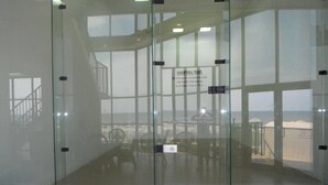 A glass-walled room with a view of a beach and a sign indicating the room is for a specific purpose.