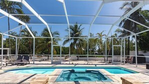 A pool area with a hot tub, lounge chairs, and a covered seating area. - Sombrero Beach | Canalfront Pool Home + Dock (Marathon)
