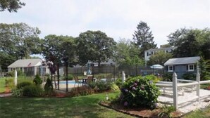 A residential property with a fenced backyard, a swimming pool, and a small garden with flowers. - Peaceful 2 Bdrm Cottage WiFi A/C Ingrd Pool & Walk To Beach! (Dennis)