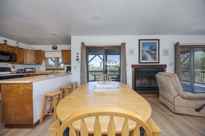 A kitchen with wooden cabinets, a dining table with chairs, a fireplace, and a view through the glass doors.