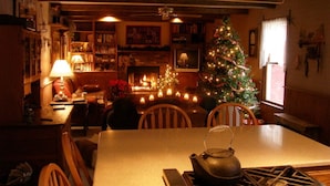 A cozy kitchen with a central island, a dining area with chairs, a Christmas tree, and a fireplace. - Hidden Hollow Farm - Pool; Game Rm; Sleeps 26, 45 min. to DC, Weddings/Corporate (Warrenton)