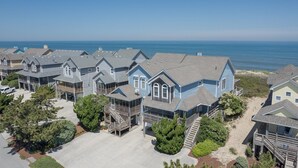 Zona residencial costera con casas de techos a dos aguas y terrazas de madera, con vistas al mar.