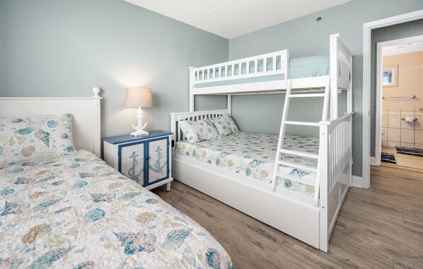 A child’s bedroom with bunk beds, a nightstand, and a bed with floral bedding.
