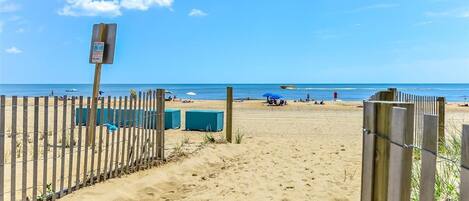 A beach with a wooden fence, a lifeguard stand, and a clear blue sky.