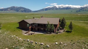 A lodge with a large deck and a view of snow-capped mountains.