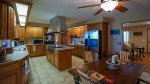 A spacious kitchen with wooden cabinets, a central island, and a ceiling fan.