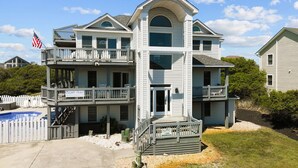 A two-story building with a balcony on the upper level, a pool in the foreground, and a sign that reads "Ocean's Grace."