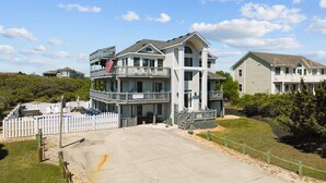 A multi-story residential building with a balcony, a flag, and a fenced pool area.