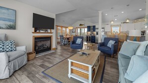 Ein geräumiges Wohnzimmer mit Kamin, gemütlicher Sitzgelegenheit und einer Küche im Hintergrund.