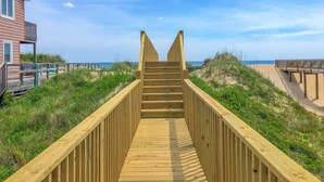 Un muelle de madera que conduce a una playa con un edificio a la izquierda.