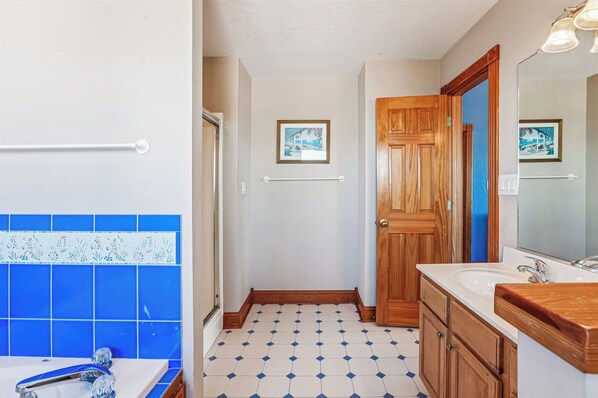 A bathroom with a white sink, wooden vanity, and a blue-tiled floor.