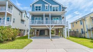 A two-story residential building with a balcony, a covered entryway, and a front yard.