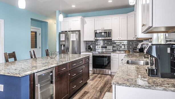 A modern kitchen with white cabinets, stainless steel appliances, and granite countertops.