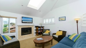 A living room with a fireplace, a television, a bookshelf, and a sofa. - 3 bdr, 3 bath Home  Walk to bay, ocean, restaurants and shops! (San Diego)