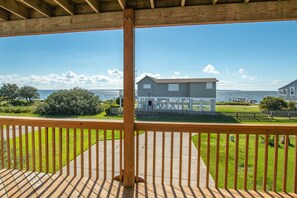 Eine Holzterrasse mit Blick auf ein Haus und ein Gewässer.