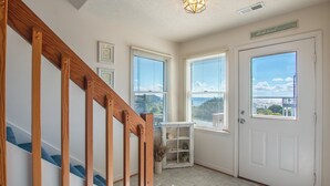 Eine Treppe mit hölzernen Geländern, eine weiße Tür mit Fenster und ein kleines Regal mit Pflanzen.