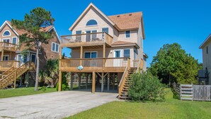Ein zweistöckiges Haus mit einem Balkon, einer Veranda und einer Treppe, die zur Veranda f ührt.