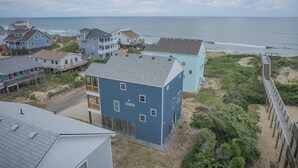 Zona residencial costera con casas, playa y un paseo marítimo de madera.