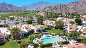 A residential area with houses, a swimming pool, and mountains in the background. - Desert Luxe | 3BR Santa Rosa Cove (La Quinta)