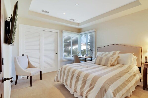 A bedroom with a bed, a chair, a desk, and a window with blinds. - Desert Luxe | 3BR Santa Rosa Cove (La Quinta)
