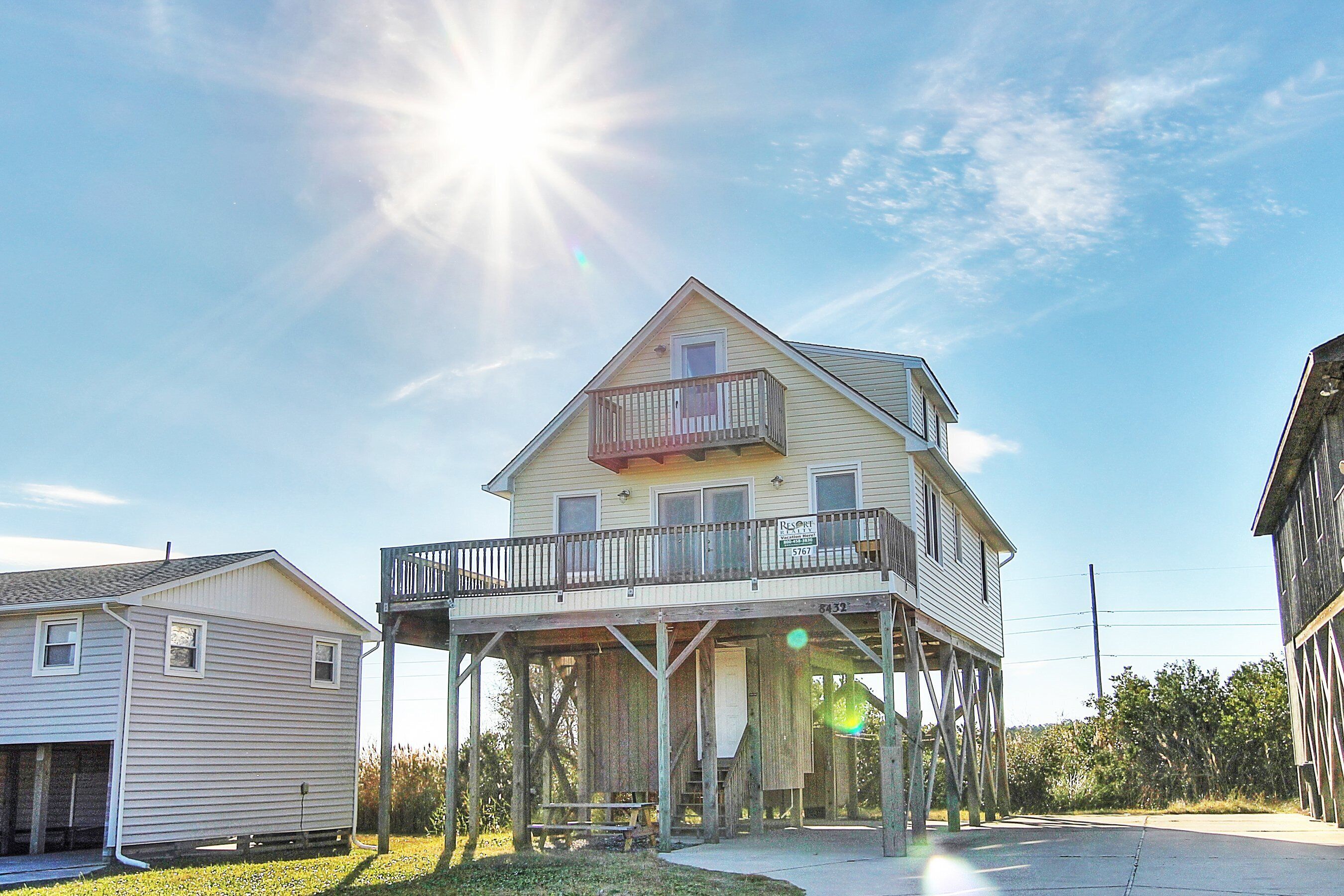 A two-story house with a balcony on the upper floor, a porch on the ground floor, and a small attached shed.