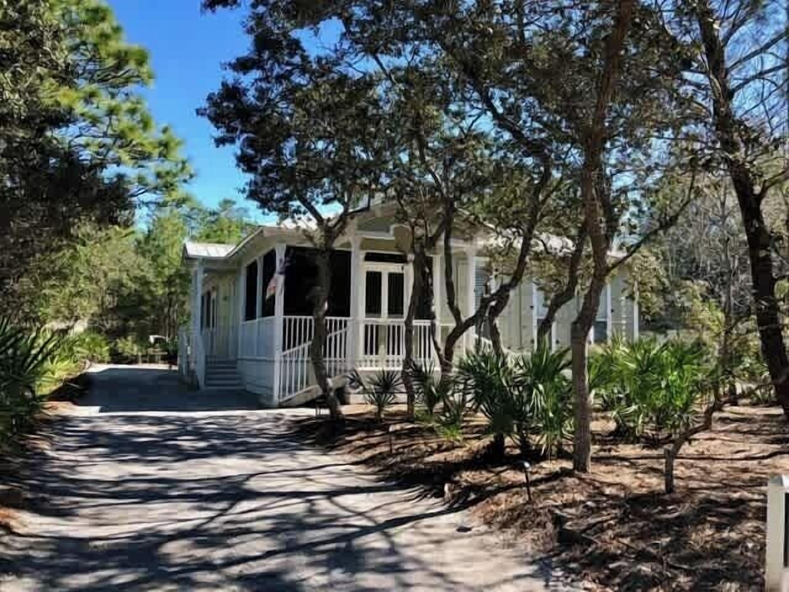 A house with a porch, surrounded by trees and a pathway.