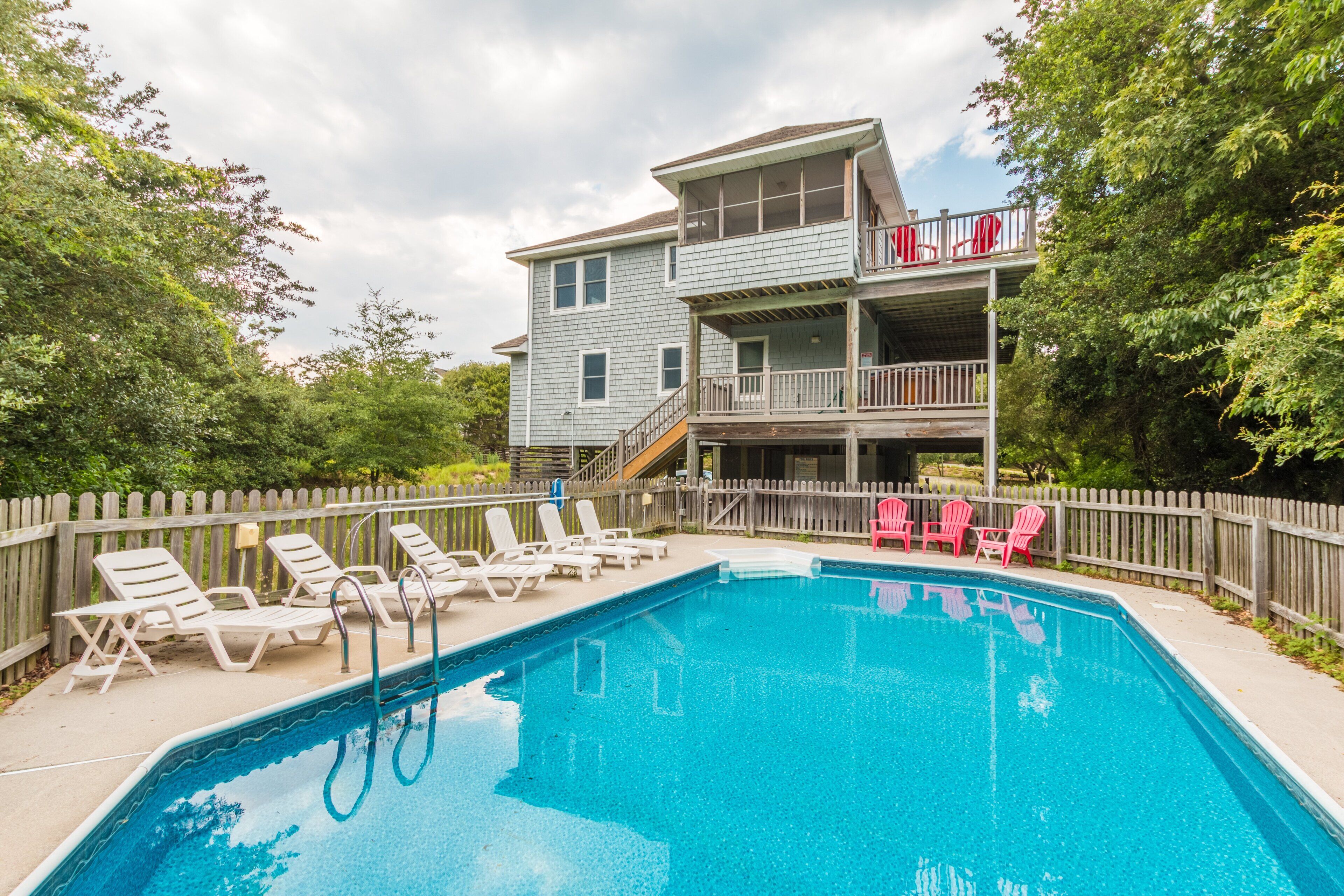 A swimming pool with lounge chairs and a wooden deck.