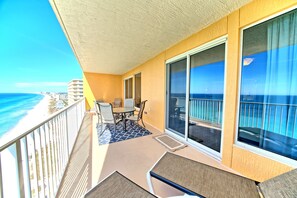 Varanda com mesa e cadeiras, vista para a praia e oceano.
