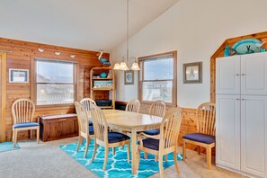 A wooden interior with a dining table surrounded by chairs, a wooden bench, and a cabinet.