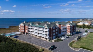 A multi-story hotel with a pool, parking lot, and a view of the ocean. - C211-Mary's Heaven - Soundfront Nags Head Condo | Near Beach (Nags Head)
